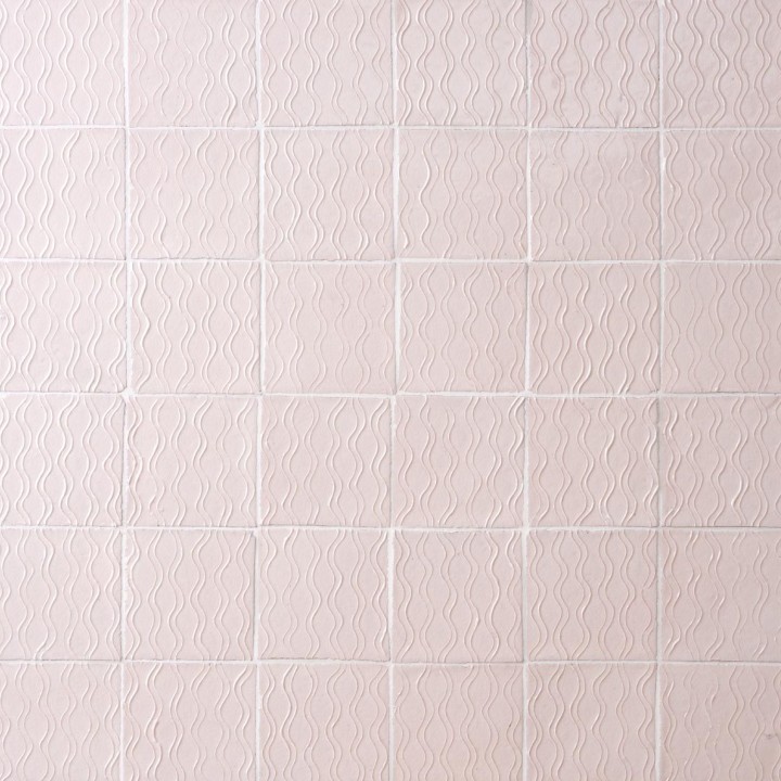 Wall of blush pink handmade square tiles with white grout