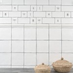 Wall of antique white square tiles with insect taco tiles and metro tiles against an oak worktop and hessian baskets