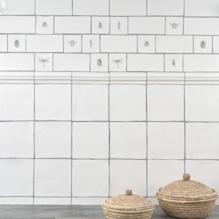 Wall of antique white square tiles with insect taco tiles and metro tiles against an oak worktop and hessian baskets