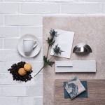 Flatlay of skinny soft green tiles with white grout in the background and kitchen hardware and accessories on top.