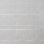 Wall of skinny soft green tiles with white grout laid in a classic brick bond pattern