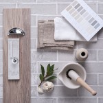 Flatlay of skinny pale grey tiles with white grout in the background and kitchen hardware and accessories on top.