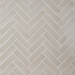 Wall of skinny pale green tiles with white grout laid in a herringbone pattern