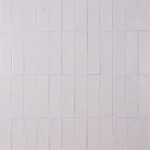 Wall of skinny chalk white tiles with white grout laid in a vertical brick bond pattern
