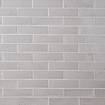 Wall of skinny pale grey tiles with white grout laid in a classic brick bond pattern