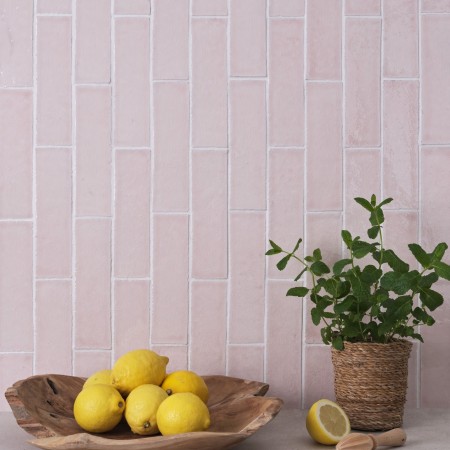 Wall of skinny blossom tiles with white grout behind a fruit bowl and house plant