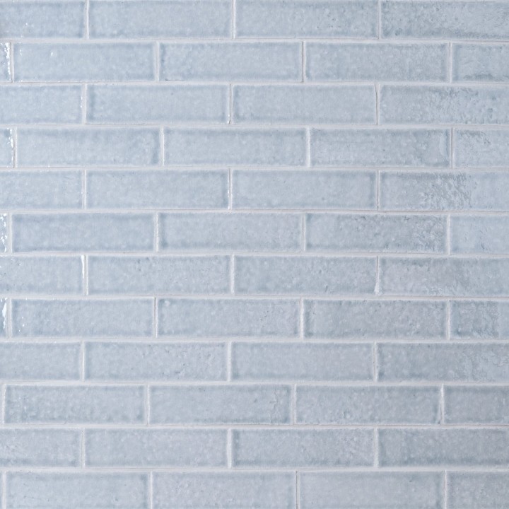 Wall of skinny blue tiles with silver grey grout laid in a classic brick bond pattern