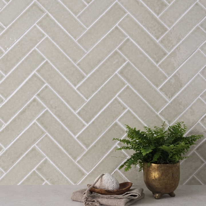 Wall of skinny soft green tiles with white grout behind a house plant