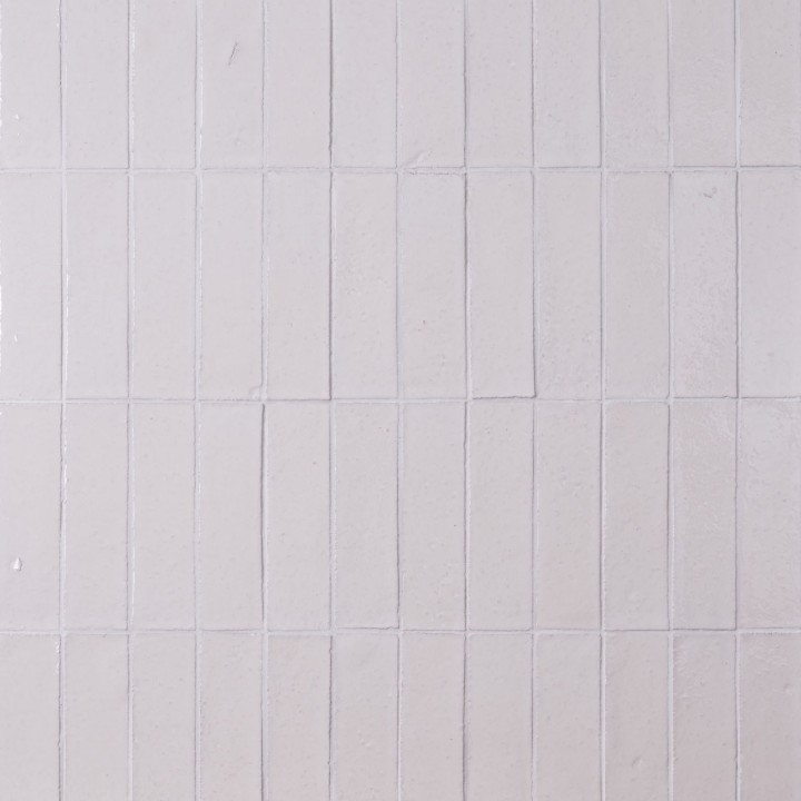 Wall of skinny chalk white tiles with white grout laid in a vertical brick bond pattern