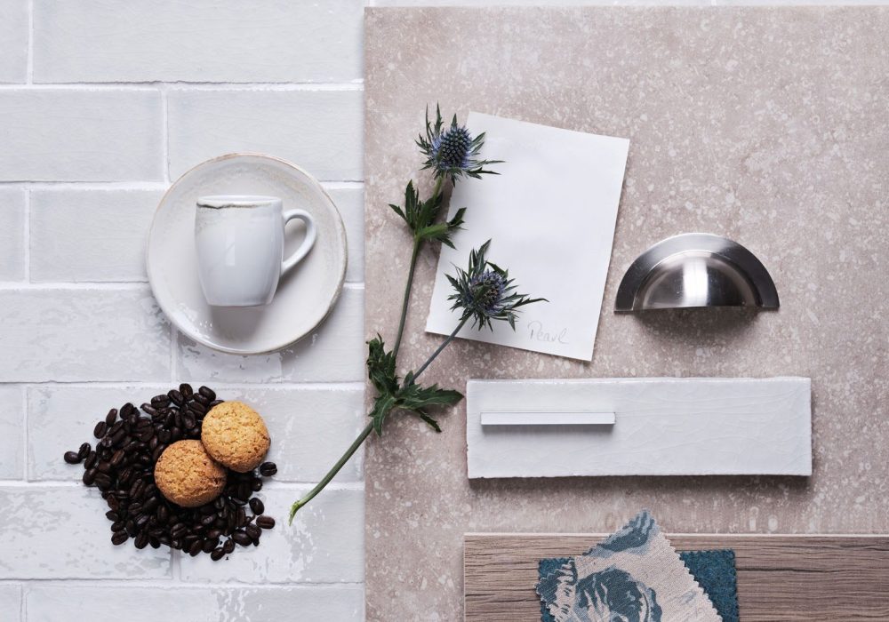 Flatlay of skinny soft green tiles with white grout in the background and kitchen hardware and accessories on top.
