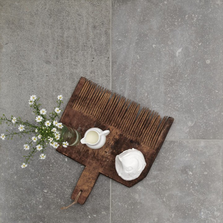 Floor of grey stone effect porcelain floor tile with Medium Grey grout with chopping board on top