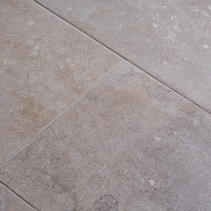 Close up of warm stone effect porcelain floor tile with Beige grout at an angle