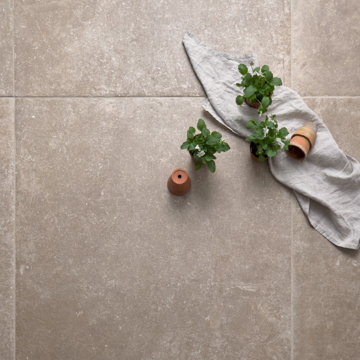 Warm brown stone effect square porcelain floor tile with beige grout and some terracotta pots