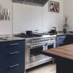 White long brick tiles as a kitchen splash back behind a stainless steel range cooker and navy kitchen cabinets