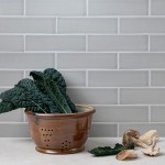 Wall of skinny pale green matt metro tiles with silver grey grout styled with a copper bowl