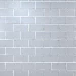 Wall of pale blue matt tiles with silver grey grout laid in a Brick Bond tile pattern