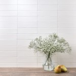 Wall of skinny white matt metro tiles with white grout styled with a glass vase and cow parsley