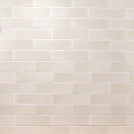 Wall of skinny parchment white matt metro tiles with white grout laid in a brick bond pattern