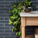 Wall of slate blue skinny metro tiles laid in a brick bond tile pattern behind a vanity unit and devils ivy