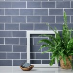 Wall of matt slate blue metro tiles paired with white grout and styled with a frame and boston fern