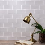 Wall of stone grey matt metro tiles with white grout styled with a lamp and book