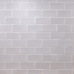 Wall of stone grey matt tiles with silver grey grout laid in a brick bond tile pattern