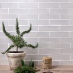 Wall of skinny metro stone grey matt tiles with white grout styled with an stoneware plant pot