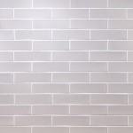 Wall of skinny stone grey matt tiles with white grout laid in a brick bond tile pattern