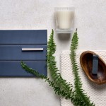 Flatlay of matt slate blue wall tiles and a sandstone floor with a candle and fern leaves