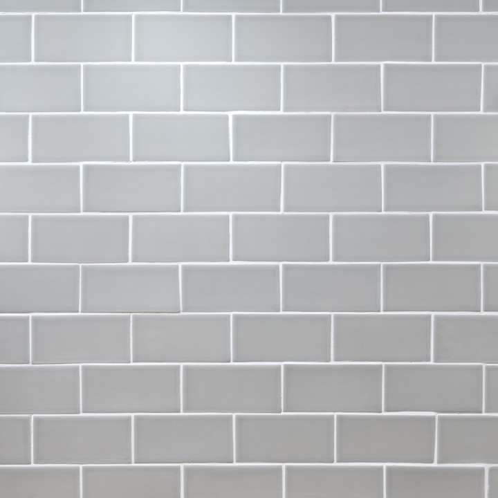 Wall of pale green matt metro tiles with white grout laid in a brick bond tile pattern