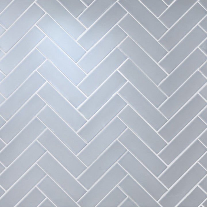 Wall of skinny pale blue matt metro tiles with silver grey grout laid in a herringbone tile pattern