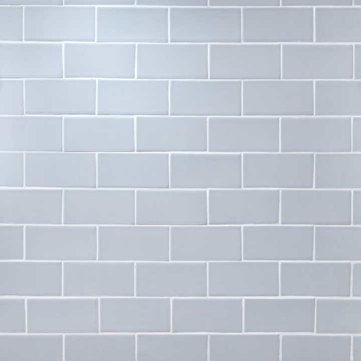 Wall of pale blue matt tiles with silver grey grout laid in a Brick Bond tile pattern