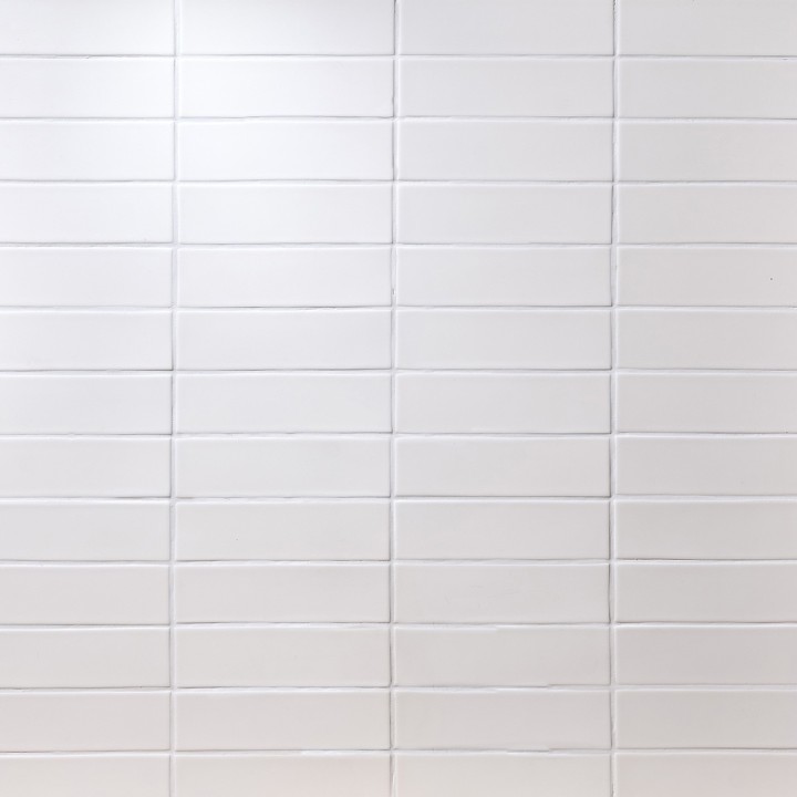 Wall of white skinny metro matt tiles with white grout stacked in a horizontal tile pattern