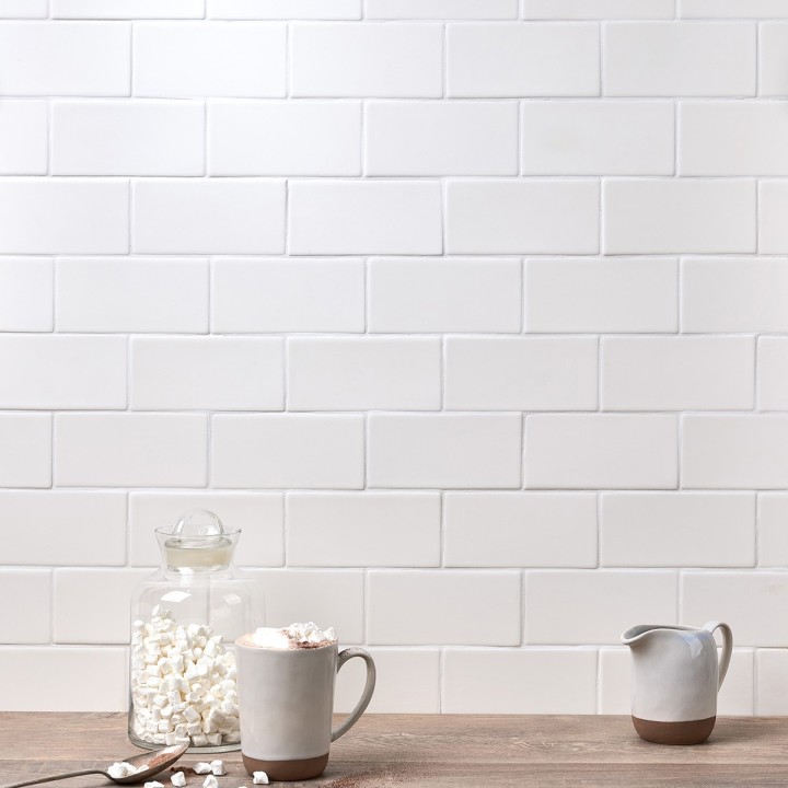 Wall of white matt metro tiles with white grout styled and couple of mugs and marshmallows