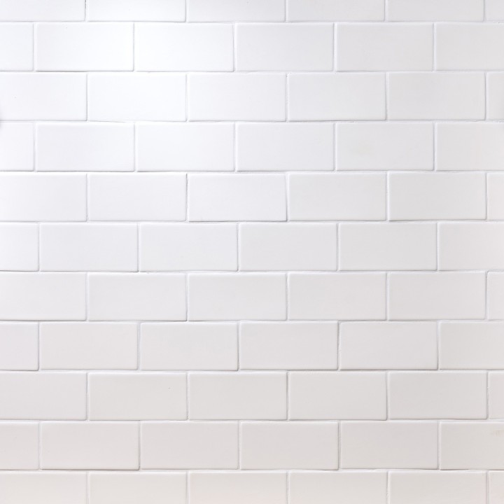 Wall of white matt metro tiles with white grout laid in a brick bond tile pattern