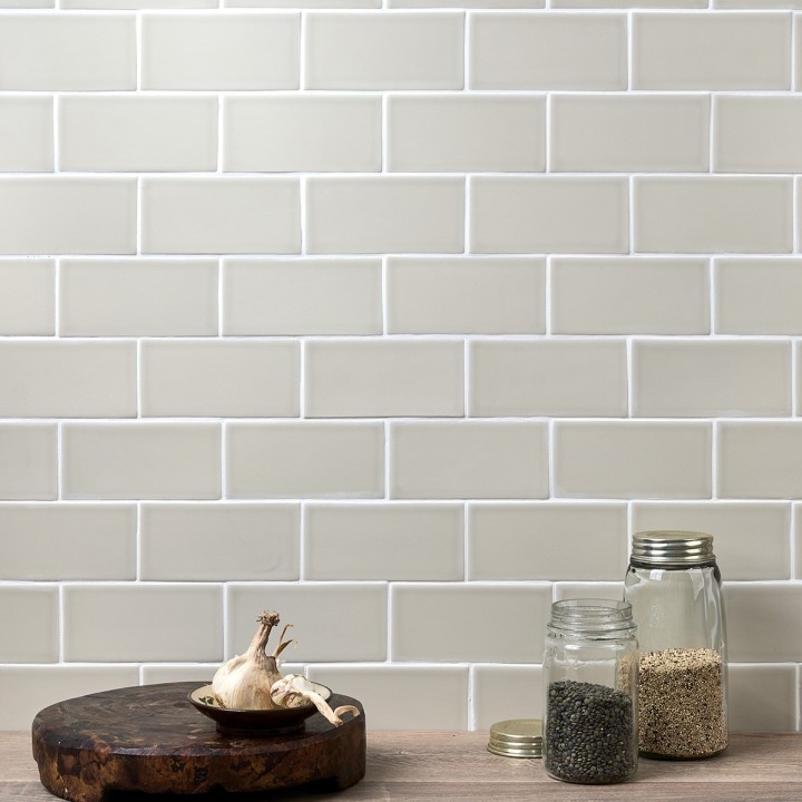 Wall of sage green metro matt tiles with white grout styled with jars and a chopping board