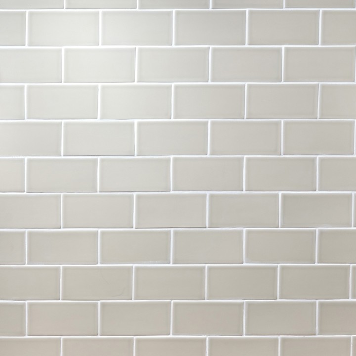 Wall of sage green metro matt tiles with white grout laid in a brick bond tile pattern