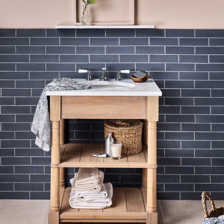 Sandstone porcelain floor tile across a floor with a paired with a matt slate blue tile and pine vanity