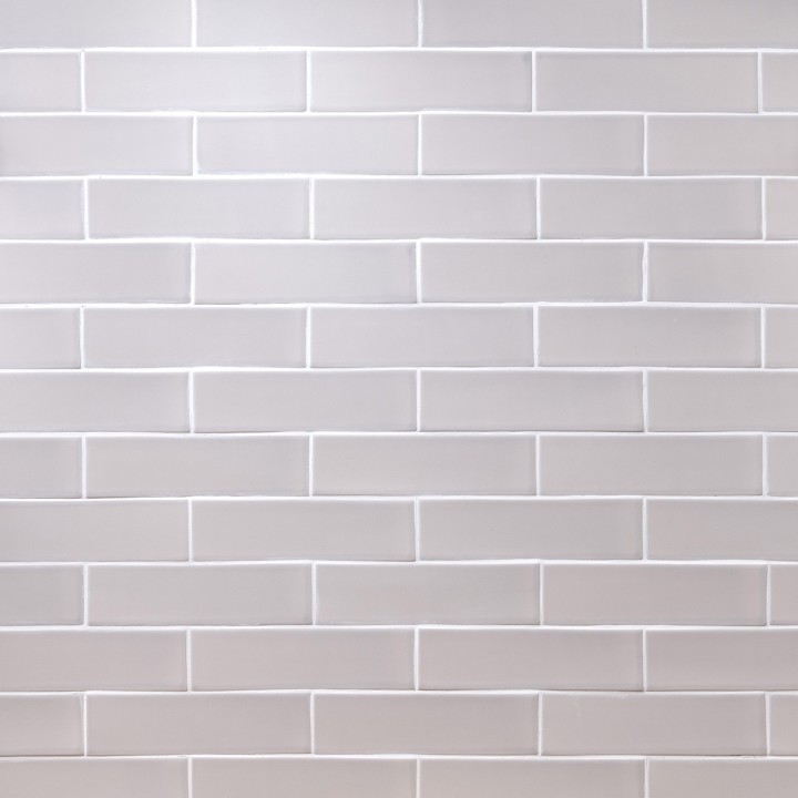 Wall of skinny stone grey matt tiles with white grout laid in a brick bond tile pattern