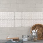 Wall of beige metro tiles with a strip of pendragon pattern tiles behind a slate work top