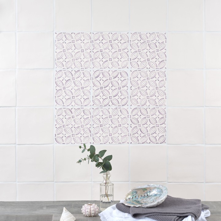 Wall of ivory square tiles framing a 9 pink pattern tiles behind a grey worktop with small accessories
