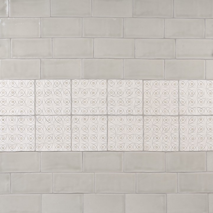 Wall of beige metro tiles with a strip of pendragon pattern tiles