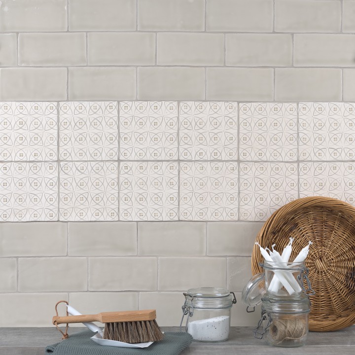 Wall of beige metro tiles with a strip of pendragon pattern tiles behind a slate work top