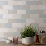 Wall of a mixture of medium brick metro tiles in blues, greys and off-whites behind an oak top and kitchen accessories