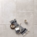 Floor of warm grey stone effect porcelain floor tiles with Beige grout and a scarf and coffee