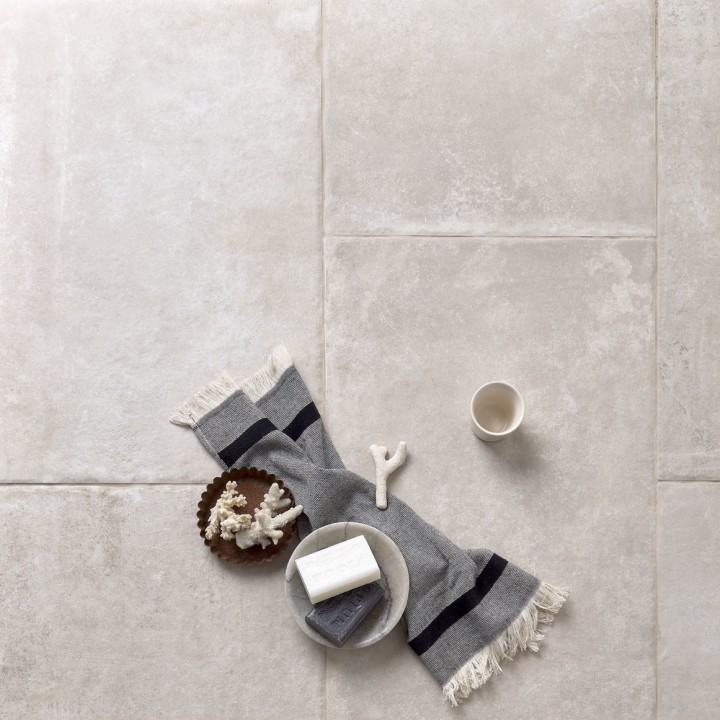 Floor of warm grey stone effect porcelain floor tiles with Beige grout and a scarf and coffee
