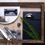 Flatlay of a navy brick tile ontop of a limstone porcelain tile, framed with an ornate wooden frame.