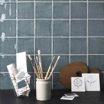 Wall of square grey blue handmade wall tiles behind a slate top and artist accessories