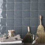 Wall of square dark grey blue handmade wall tiles behind a grey wood work top and pantry accessories