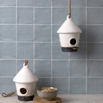 Wall of square medium grey handmade wall tiles behind a grey wood work top and bird feeders